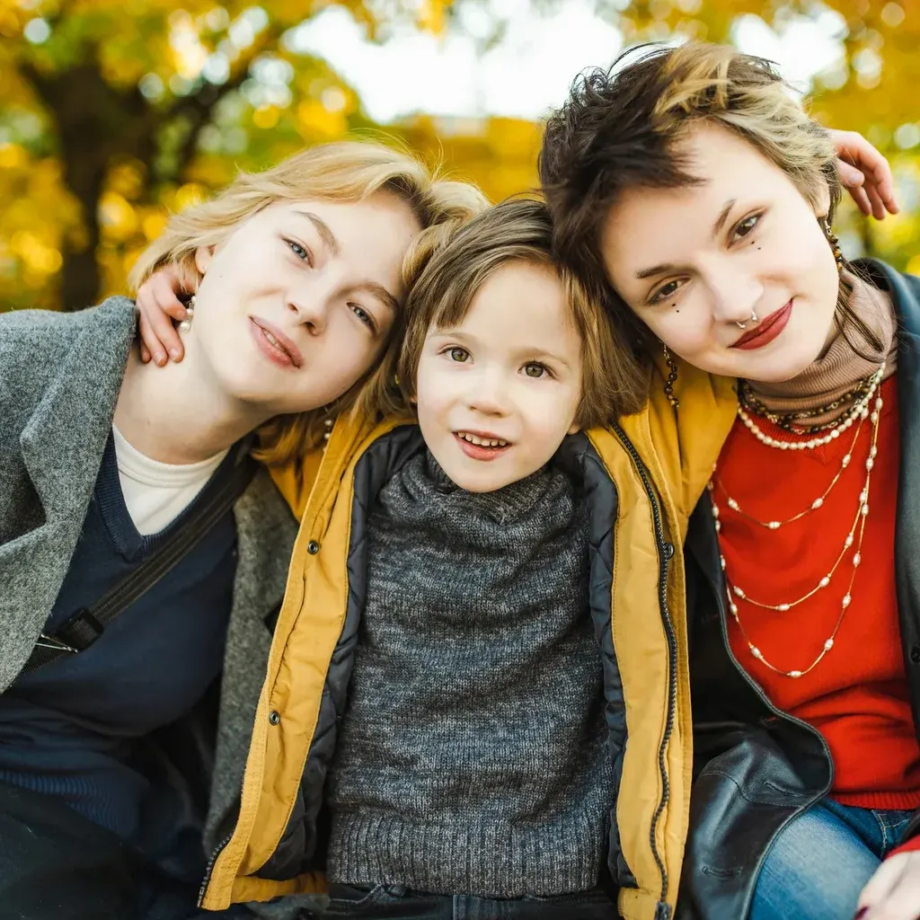 A mother hugging her two children outdoors in autumn